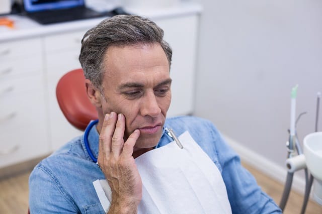 unhappy man with toothache touching his cheek