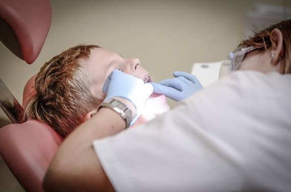 pediatric dentist checking boy's teeth