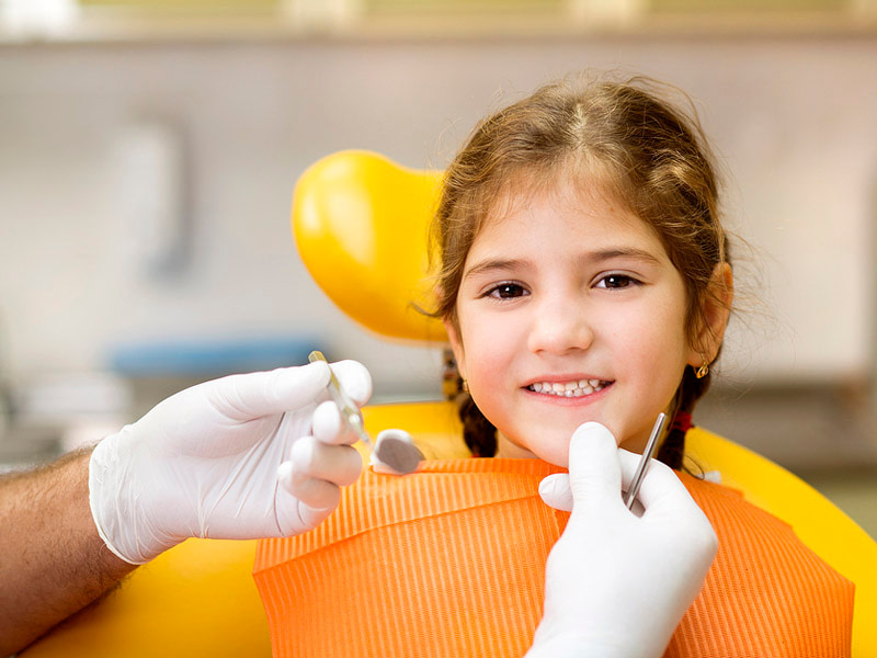 Little girl sitting and smiling on dentist chair