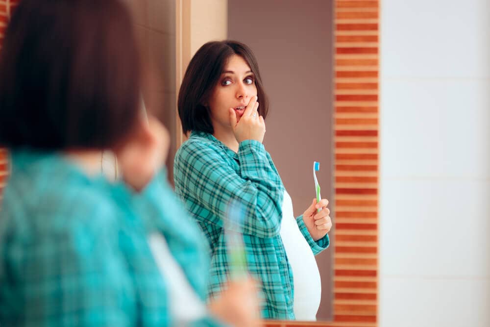 pregnant woman with toothache looking at a mirror